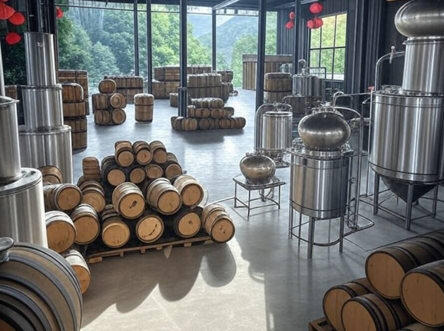 Destilaria moderna de whisky single malt inaugurada na China pela Diageo, com barris e equipamentos de destilação.